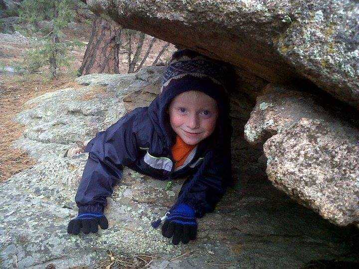 Alex, at four years, old climbing between rocks on a hike.